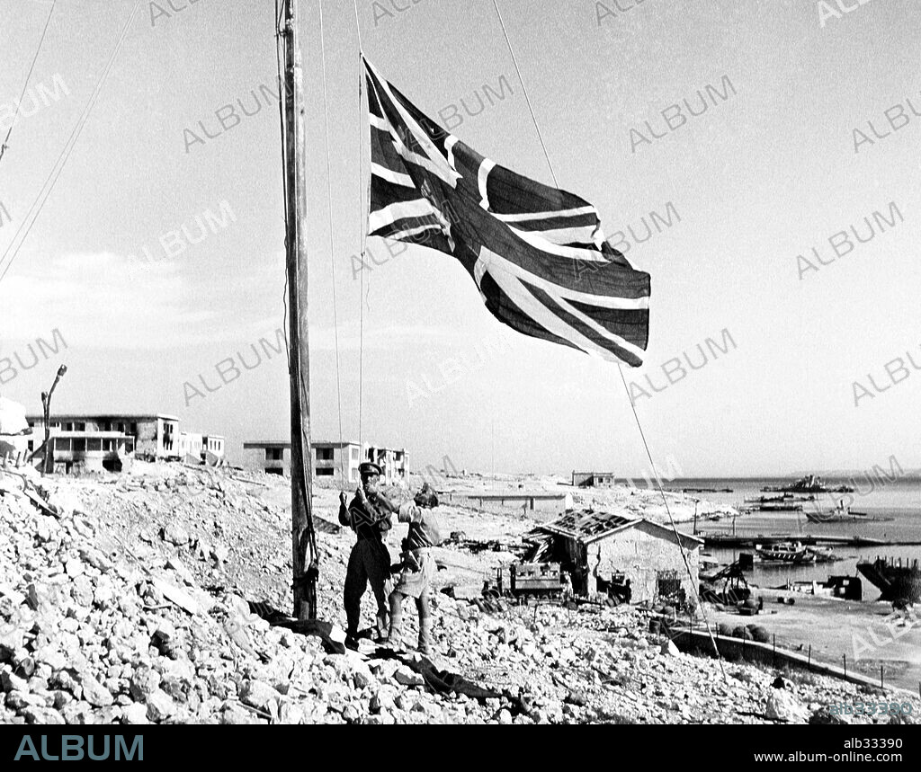 Tobruk.The Union Flag or Jack is hoisted in Tobruk in place of the swastika.The british tommy stands symbolically on the swastika as he raises the Union Jack up into the breeze. November 1942.