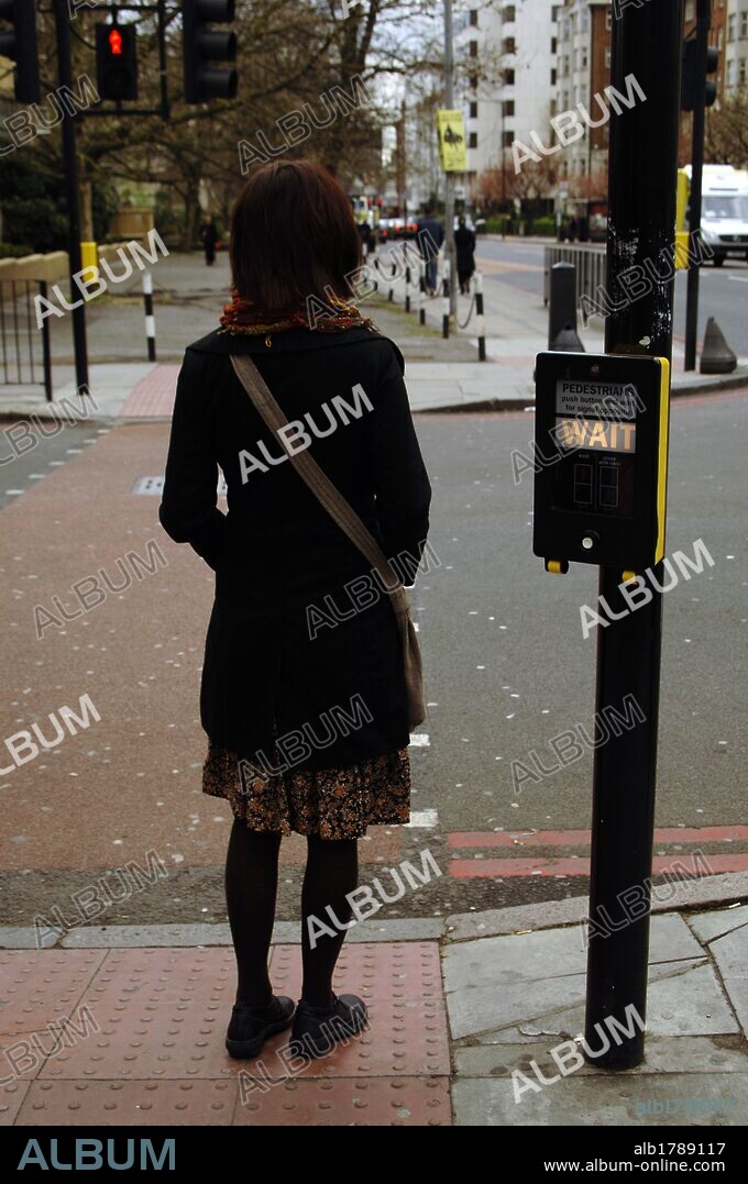 Chica esperando a que el semáforo de peatones esté en verde para poder cruzar la calle. Hampstead. Londres. Inglaterra. Reino Unido.