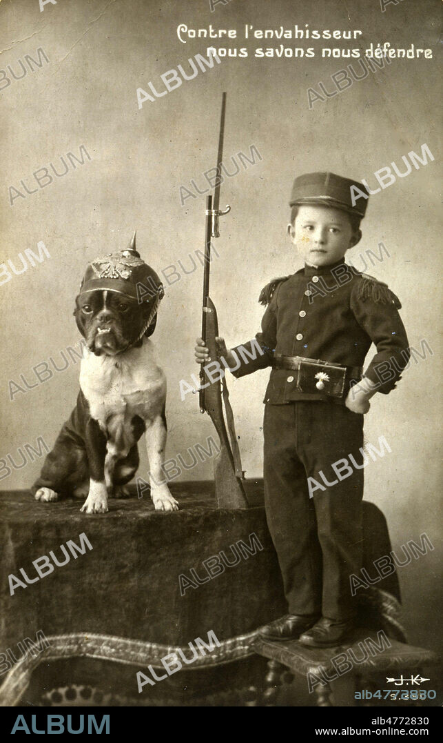 'Contre l'envahisseur nous savons nous defendre' declare un enfant portant un fusil, a cote d'un chien coiffe d'un casque a pointe. Photographie anonyme pour une carte postale vers 1915. Credit : Jean Vigne/KHARBINE-TAPABOR.