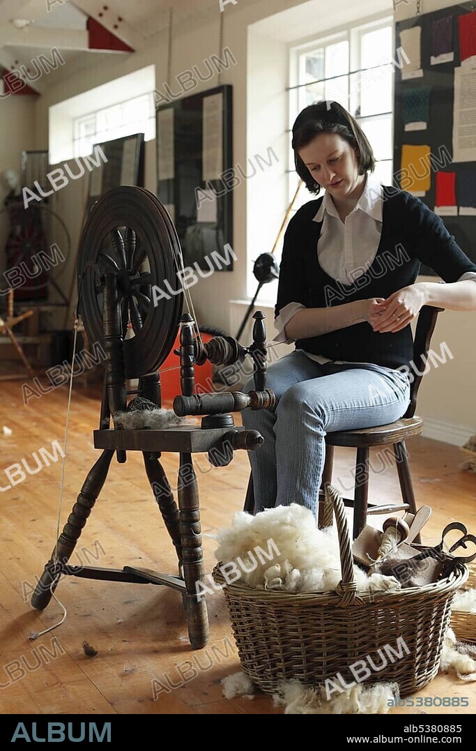 Young woman sitting at a historical spinning wheel, The Sheep and Wool Centre, Leenane, Connemara, County Galway, Republic of Ireland, Europe.