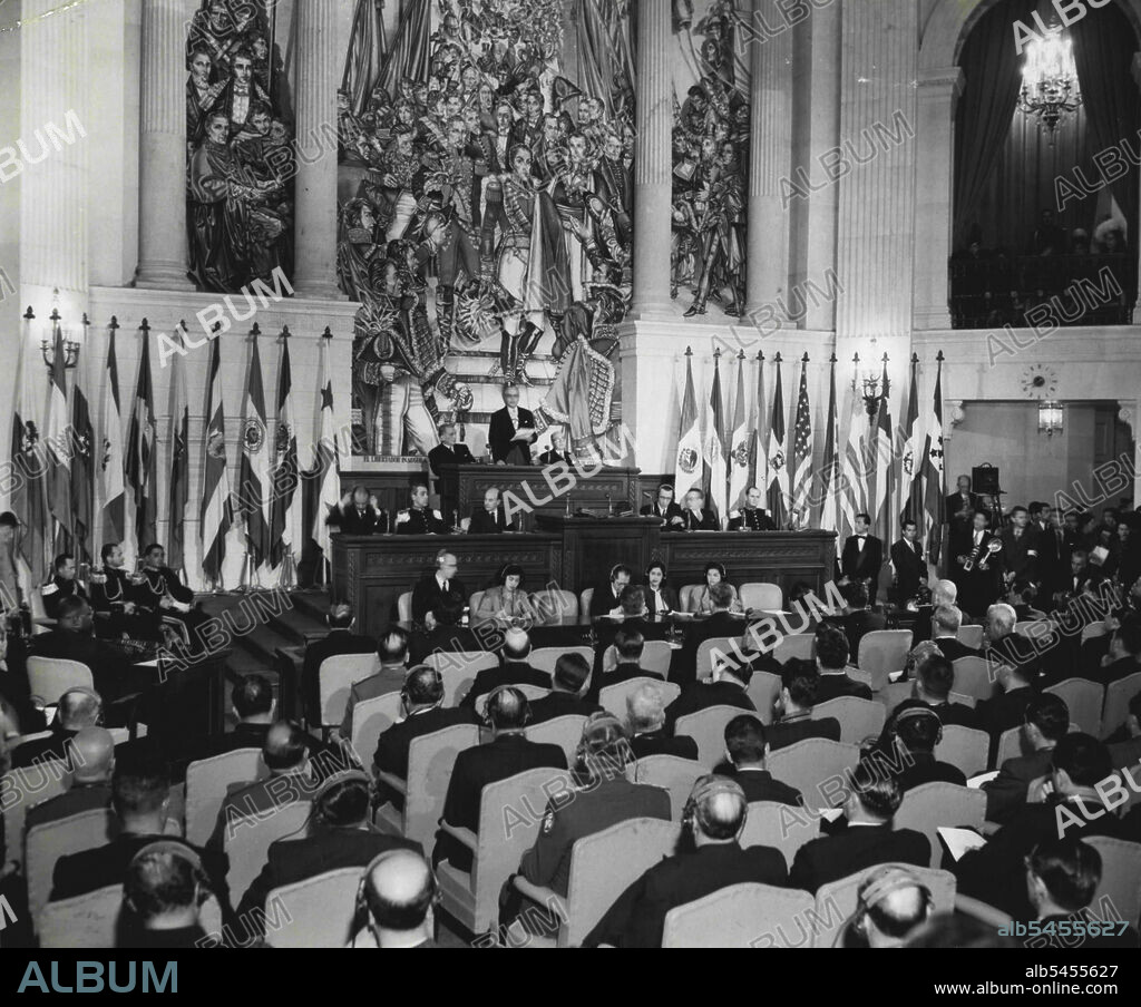 Pan American Session In Bogota - Flanked by the flags of the Pan American Countries, Colombia's President Mariano Ospina Perez on March 30 opens the ninth annual conference in the chamber of deputies in the National Capitol at Bogota, Colombia, which was reported wrecked, April 9, by mobs armed with guns and machetes. U.S. state department in Washington sadd the April  9th session of the conference was broken up by the uprising but all our delegates were safe. September 04, 1948. (Photo by Associated Press Photo).