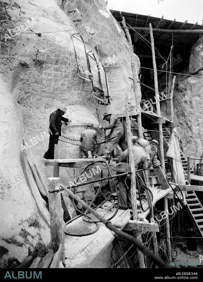 Borglum oversees work on Mount Rushmore. John Gutzon de la Mothe Borglum (March 25, 1867 - March 6, 1941) was a Danish-American artist and sculptor famous for creating the monumental presidents' heads at Mount Rushmore, South Dakota; the famous carving on Stone Mountain near Atlanta; and other public works of art. He died in 1941 at the age of 73. Mount Rushmore National Memorial is a sculpture carved into the granite face of Mount Rushmore near Keystone, South Dakota. Sculpted by Danish-American Gutzon Borglum and his son, Lincoln Borglum, Mount Rushmore features 60 foot sculptures of the heads of four United States presidents: George Washington, Thomas Jefferson, Theodore Roosevelt, and Abraham Lincoln. Construction on the memorial began in 1927, and the presidents' faces were completed between 1934 and 1939. Although the initial concept called for each president to be depicted from head to waist, lack of funding forced construction to end in late October 1941. Mount Rushmore has become an iconic symbol of the United States, and attracts over three million people annually. Photographed by Charles D'Emery, undated.