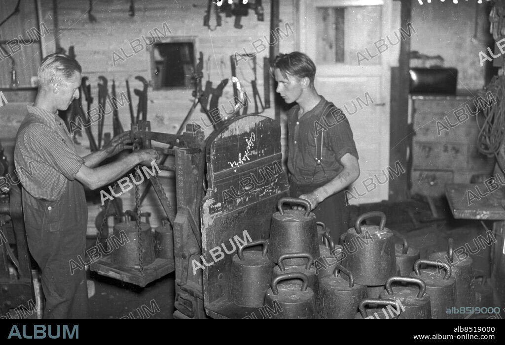 Göteborg 1941-07-31. Man med lärling väger vikter på gammaldags våg. Foto: Kamerareportage *** Local Caption *** GT Låda 1941-01. KAMERAREPORTAGE.