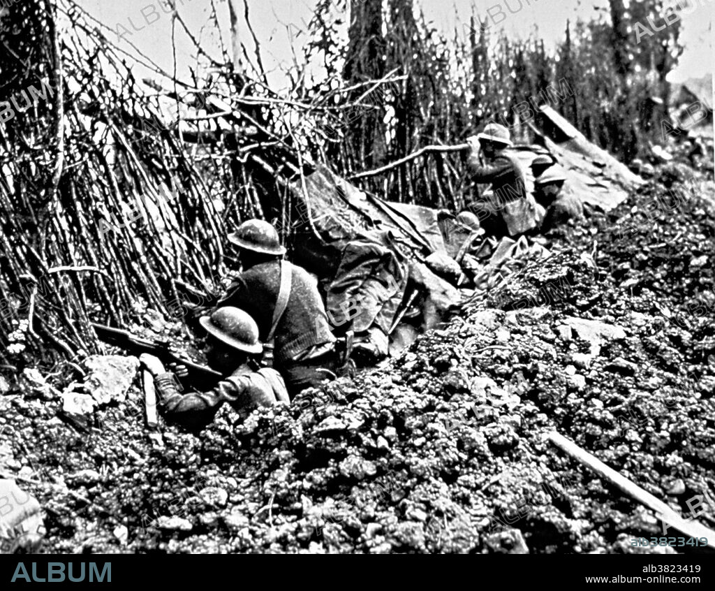 132nd Infantry in front line trench, Forges, October 3, 1918 U.S. Signal Corps photo. A line of soldiers waiting in a trench are peering through a wall of low plant growth; one man is looking through binoculars. The 132nd Infantry Regiment was organized from other Illinois militia units, namely the Illinois 2d Infantry Regiment, and activated on July 21, 1917. Assigned to the 33rd Infantry Division, it was re-designated as the 132nd Infantry Regiment and trained at Camp Logan, Texas. Sent overseas in May 1918, the 132nd participated in the Battle of Hamel, the Meuse-Argonne Offensive, and the 1918 Somme offensive. Five men from the regiment were awarded the Medal of Honor.