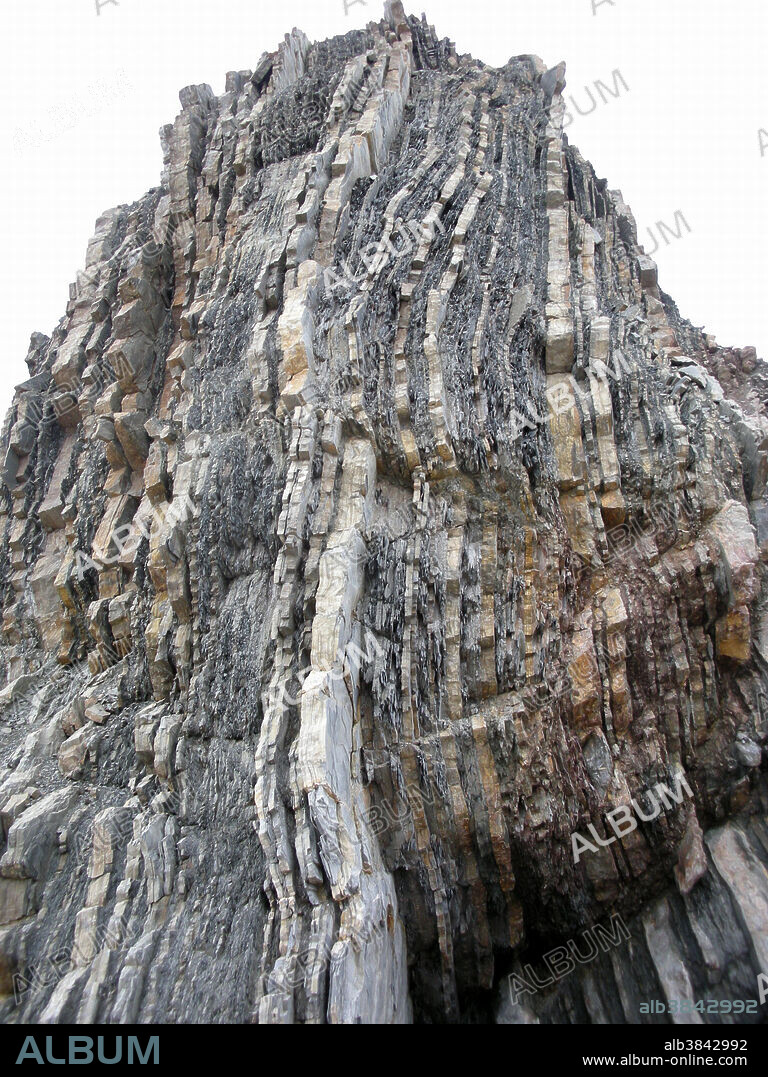 Sedimentary rock strata pushed vertical by geological action. This formation is located in Perce, Quebec, Canada.