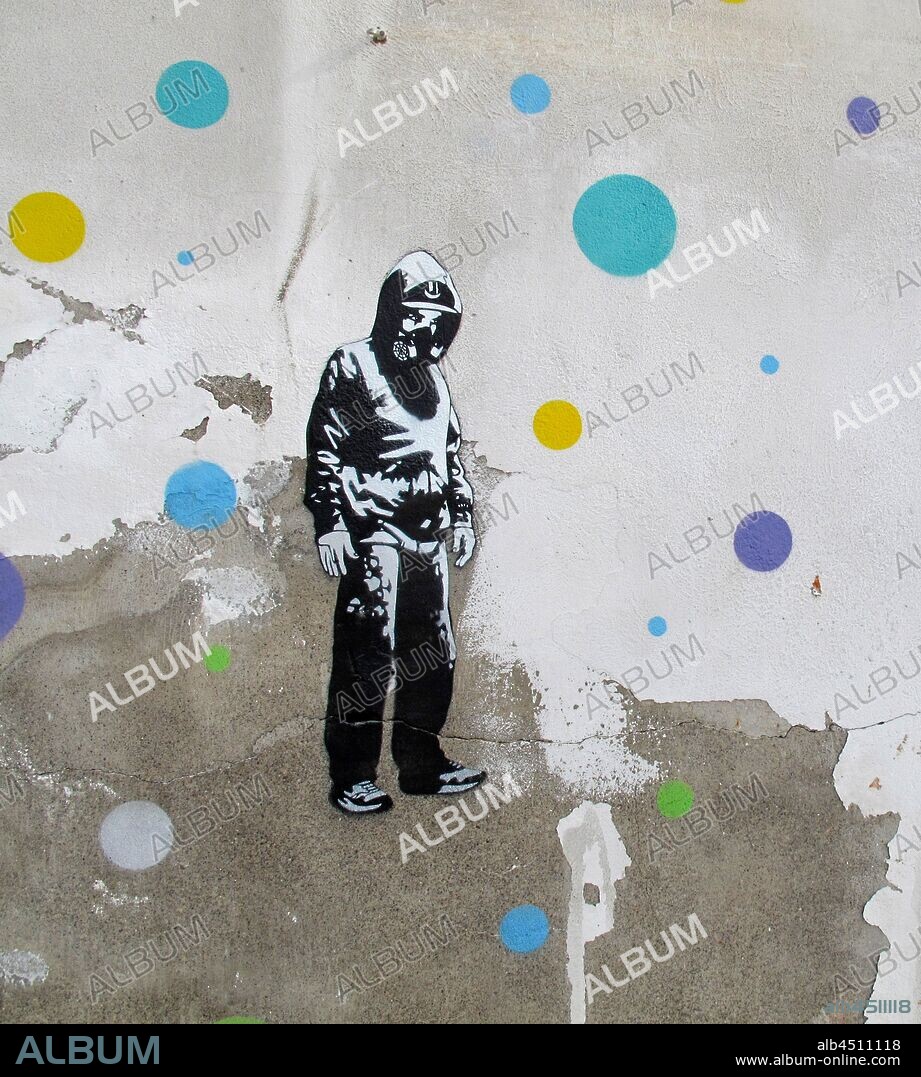 Ilustracion de joven encapuchado en blanco y negro con mascara antigas rodeado de círculos de colores, graffiti mural, Plaza de las Glorias; Distrito San Martin, Barcelona en 2014.