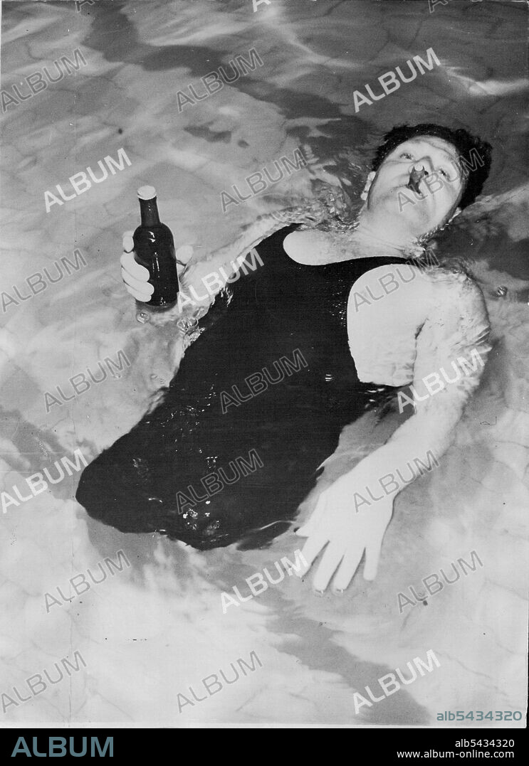 Swimming The Atlantic -- In "Queen Mary's" Swimming Pool - Charles Zimmy swimming on his back in the "Queen Mary's" swimming pool, with his indispensable cigar and a bottle of beer, as the liner left Southampton. When the "Queen Mary" left here for New York this morning, Charles Zimmy, the American Legless Swimmer, started to "Swim The Atlantic" in the calm waters of the liner's swimming pool. He smokes 15 or 20 cigars a day during his feats of endurance, and the expects to smoke over 100 cigars.