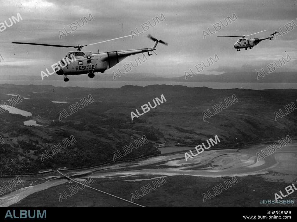 Trans-Atlantic Hover-Planes Arrive In Scotland -- Nearing the end of the first ever helicopter crossing of the Atlantic, the United States Air Force helicopters "Hopalong" and "Whirl-O-Way" pass over the coastline prior to landing at Prestwick. Stripped down until they were little more than flying fuel tanks, the two Sikorsky H-19 copters flew in hops from the Westover Air Force base in Massachusetts. Their last hop, from Keflavik Air Base in Iceland, a distance of 740 miles, took 10 hours, five minutes. Total flying time for the 3,400 mile trip in five stages was 42 hours, 25 minutes. July 31, 1952.