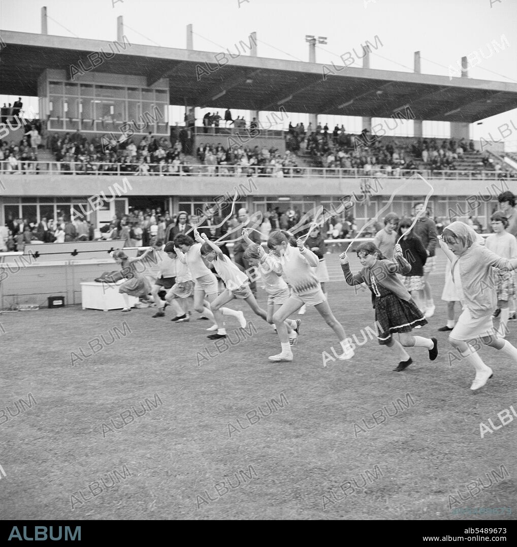 JOHN LAING PLC. Copthall Stadium, Hendon, Barnet, London, 25/06/1966. Girls leaving the starting line of a skipping race, with spectators in a stand beyond, at the annual Laing Sports Day held at Copthall Stadium. In 1966, the annual Laing employees' Sports Day was held on 25th June at Copthall Stadium in Hendon. It was the first time the event had been held there, having previously taken place the Laing Sports Ground at Elstree. A range of events included athletics and a football competition, and competitors travelled from the firm's regional offices and sites, including from Scotland and Carlisle. There was also a funfair, marching band, and sports competitions for children. The sports events were followed by a barbecue and social evening.