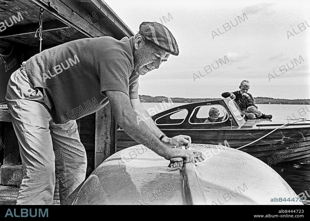 TRANÅS 1962-08-31. Lennart Hyland, tidningsman, radio- och TV-journalist, sköter om en plastjolle på sommarstället utanför Tranås. Hans söner sitter i en motorbåt i närheten. Foto: Jarl Ekenryd / RiR / SVT / Kod: 5600 Liknande bild och reportage publ. i RiR 39/62 sid. 16-17, 68 inför TV-programmet Hylands hörna. RiR 16480 sv/v neg Kepsar persons: LENNART HYLAND sites: SVERIGE;SMÅLAND.