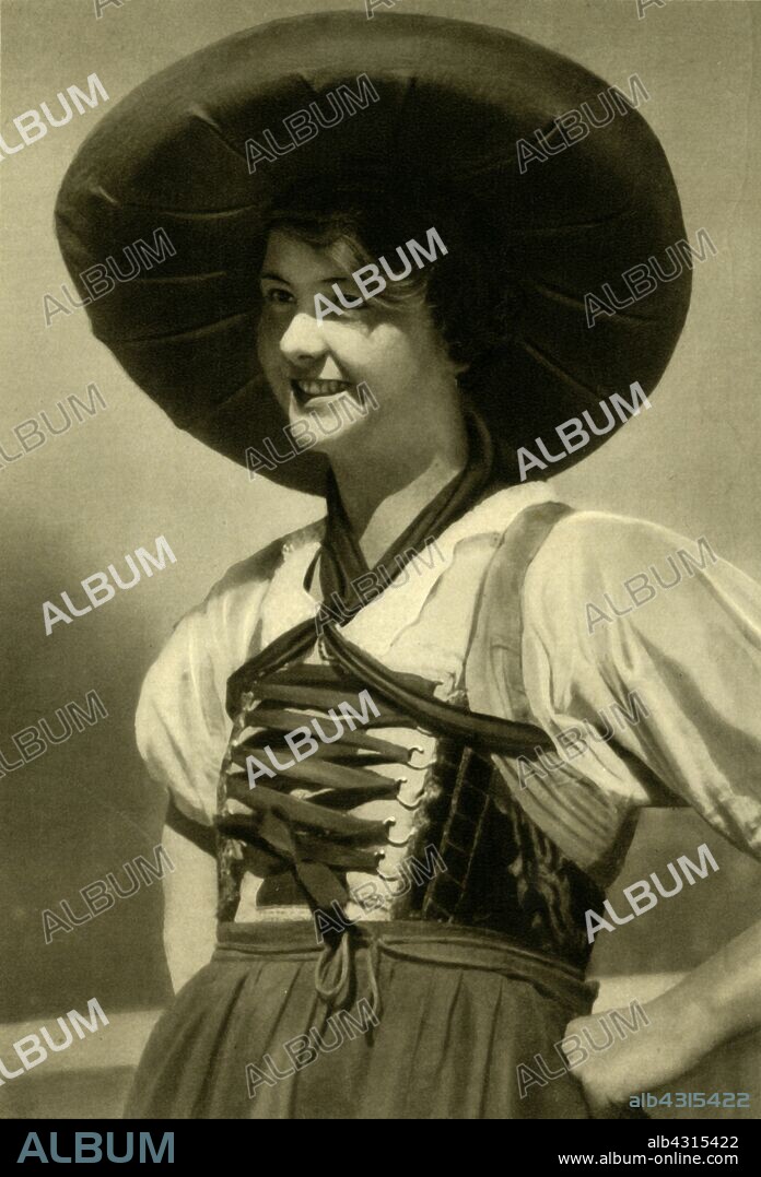 Woman in traditional costume, Tyrol, Austria, c1935. Austrian woman from the Tyrol region wearing a wide-brimmed hat and dress with laced bodice. From "Österreich - Land Und Volk", (Austria, Land and People). [R. Lechner (Wilhelm Müller), Vienna, c1935].