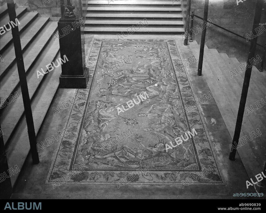 Only woman mossaic artist in the world as assistant to Boris Anrep . Celebrities as floor decorations for National Gallery . Maria Volkova , the only woman mosaic artist in the world , is assisting her cousin , Mr Boris Anrep , with his remarkable floor decorations at the National Gallery in Trafalgar square , London . The design consists of eleven figures , ten of them representing well known people in Society and on the stage . The eleventh is a mystery figure . the persons whose features are being immortalised in stone are all personal friends of Mr Anrep . Among them are Mr Osbert Sitwell as Apollo , Mrs Ryan Guiness and Lady Jowitt . Photo shows : The finished mosaic by Russian artist , Boris Anrep , ' The Awakening of the Muses ' , at the National Gallery , London . 24 June 1933.
