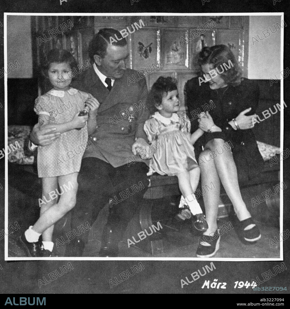 Orig. bildtext... HITLER AND EVA with two unidentified children, might be his; Orig. bildtext... FROM THE PHOTOGRAPH ALBUM owned by Eva Braun, Hitler's supposed wife, recently discovered by the americans at Franfurt. A family scene? Hitler and Eva Braun with two children. Orig. bildtext... ARE THESE ADOLF'S AND EVA'S? Frankfurt, Germany... found in Eva Braun's treasure chest here recently was this snapshot showing Eva Braun and Adolf Hitler and two unnamed children who may have been the offspring of der Fuehrer and the one-time carpenter's daughter. Although there had been various stories that Hitler and Eva had wed just before they were supposed to have committed suicide in April of this year, evidence to bolster the stories had never been forthcoming. The child seated between Adolf and Eva here is the blonde three-year-old known as Uschi. The snapshot was dated 1944. Anm. Privatfoto ur Eva Brauns fotoalbum. För komplett text, se originalet. persons: EVA BRAUN;ADOLF HITLER sites: TYSKLAND PhotoDate:1944-03-??.