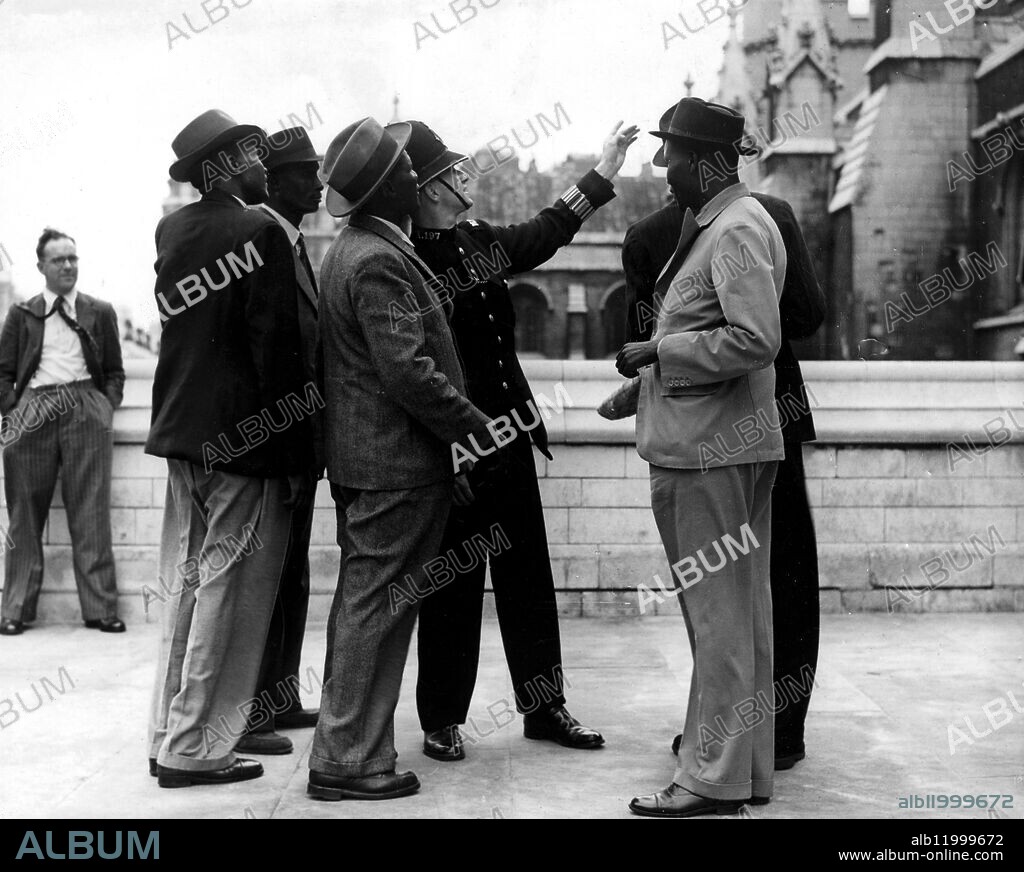 A party of four East African Chieftans and a Native Councillor who have been studying agriculture in Sussex, were to be seen in London today when they visited the House of Commons. PC Milton points out items of interest at the House of Commons to the native party. 25th August 1948.