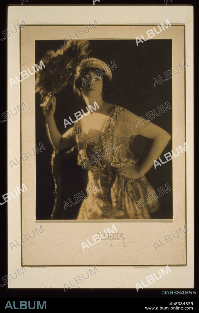 ADOLPH DE MEYER. Three-quarter length portrait of Gertrude Vanderbilt Whitney (Mrs. Harry Payne Whitney) wearing a jeweled gown and tiara and holding a peacock feather fan, c1916. (American sculptor, patron of the arts and collector Whitney founded the Whitney Museum of American Art in New York City).