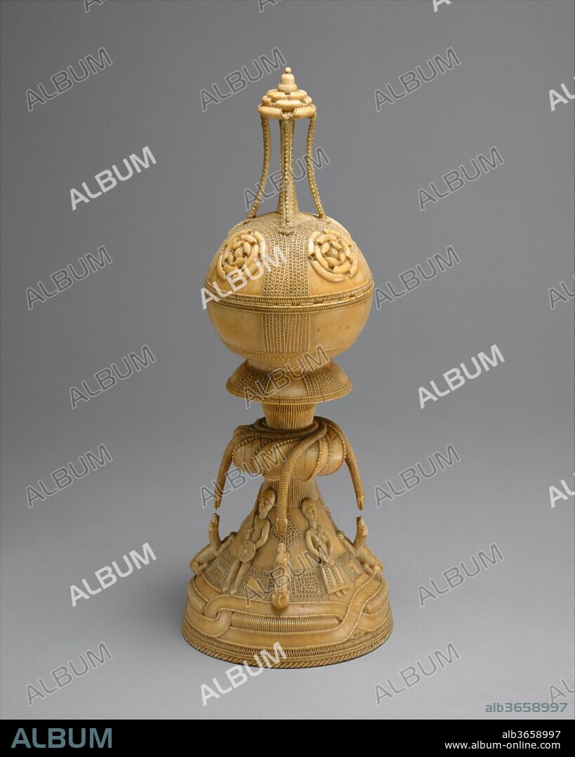 Lidded Saltcellar. Culture: Sapi-Portuguese. Dimensions: H. 11 3/4 x Diam. 4 1/4 in. (29.8 x 10.8 cm). Date: 15th-16th century.
This saltcellar is both an extraordinary example of skilled workmanship and an artifact that epitomizes a singularly important convergence of cultures. In the second half of the fifteenth century, Portuguese explorers and traders were impressed by the considerable talent of ivory carvers along the coast of West Africa. As a result, they were inspired to commission works of this kind for their patrons, which ingeniously combine both European and African aesthetics and forms. During this period, salt and pepper were costly commodities and elaborate receptacles were appropriate for their storage in princely homes.
This work contains imagery relating to indigenous Sapi belief systems. The four snakes, associated with mystical wealth, appear to confront four growling dogs. According to regional traditions, dogs are considered spiritually astute animals able to see spirits and ghosts that are invisible to humans. This depiction of the dogs, with teeth bared, hair bristling, and ears laid back, may relate to that ability. However, the level of animation in this scene could also derive from chivalric hunting scenes in European woodcuts, which were furnished to local African artists by their European patrons.