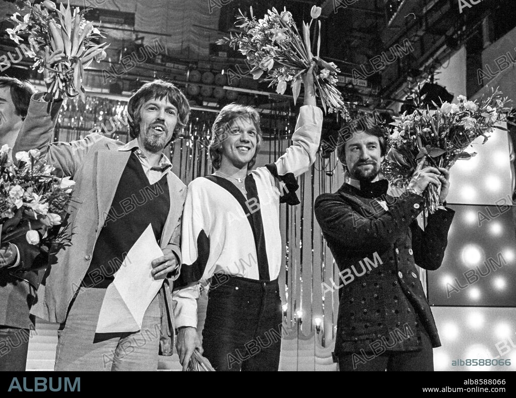 STOCKHOLM 1978-02-11. Sångaren och musikern Björn Skifs (mitten) med blommor i handen omgiven av låtskrivaren Peter Himmelstrand (tv) och producenten Bengt Palmers (th) efter segern i Melodifestivalen med sångbidraget "Det blir alltid värre framåt natten" på Cirkus i Stockholm 11:e februari 1978.. Foto: Olle Lindeborg / TT / Kod. 190.