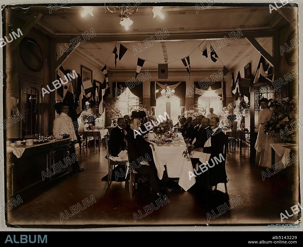 Atelier J. Hamann, Johann Hinrich W. Hamann, festive plaque, silver gelatin paper, black and white positive process, total: height: 18.10 cm; width: 23.90 cm, titled and dated: verso: handwritten in lead: Hamburg, 1909, festive plaque, in another hand handwritten in lead, for, ( ) Stellmacher, Auswandererhallen, studio for photography of all kinds awarded Hamburg 1898, J. Hamann, Hamburg 36, Holstenplatz, 14, reporting photography, portrait photography, table decoration, group portrait, festivities, man, woman, tablecloth, food and drink, flag, color (state symbol), set table/tableware, table decoration, flowers, Hamburg.