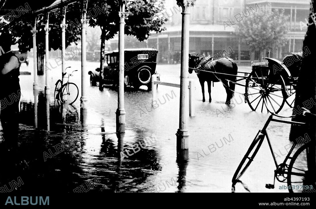 Negative - Floodwaters in Murphy Street, Wangaratta, Victoria, circa 1930, Floods in Murphy Street, Wangaratta. A horse and cart and a car are in the floodwaters. There are two bicycles leaning against verandah posts.