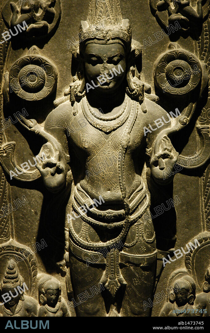 SURYA. Dios del Sol. S. IX-X (S. IX-S. X). Representacion de Surya sosteniendo dos flores de loto y sobre una carroza tirada por siete caballos. A sus pies, unas figuras femeninas, las diosas del alba y el crepúsculo, que ahuyentan a los demonios de la oscuridad con arco y flechas. Museo de Pérgamo. Berlín. Alemania.