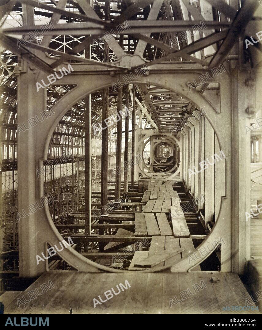 Entitled: "The Upper Gallery" photographed by Philip Henry Delamotte, 1854. This picture depicts the reconstruction of the upper gallery of the Crystal Palace in 1854. The first example of prefabricated architecture, Sir Joseph Paxton's glass and iron structure was originally built in 1851 to house "The Great Exhibition of the Works of Industry of All Nations", a mammoth exposition of technological marvels and historical exhibits from around the world. The building's modular structure, bolted ironwork fitted with 900,000 feet of precut glass, was shockingly modern, its appearance directly revealing the materials and process of its construction. The Crystal Palace proved so popular with spectators that it was disassembled and rebuilt in Sydenham, south of London, where it was used as a museum and concert hall until its destruction by fire in 1936. Delamotte's pictures of the Crystal Palace's reconstruction are among the medium's first photographic images created to document the marvels of modern engineering. Its design generated by the speeding recession of the structure's ironwork, this photograph seems to reflect the new medium's inherent and perhaps unique ability to capture the advent of modernity.