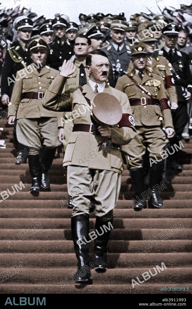 Nuremberg Rally, 7th Party Congress, the 'Rally of Freedom', Germany, 1935. With his hand raised in acknowledgement of salutes, Chancellor Adolf Hitler (1889-1945) walks down the steps to the Zeppelinfeld during Reichsparteitag (Reich Party Day) ceremonies in Nuremberg. Hitler's deputy, Rudolf Hess (1894-1987), is immediately behind him. The Nazis 7th Party Congress was named the 'Rally of Freedom' in celebration of Germany's liberation form the Treaty of Versailles epitomised by the Nazis' reintroduction of compulsory military service. A print from Adolf Hitler. Bilder aus dem Leben des Führers, Hamburg: Cigaretten/Bilderdienst Hamburg/Bahrenfeld, 1936. (Colorised black and white print).