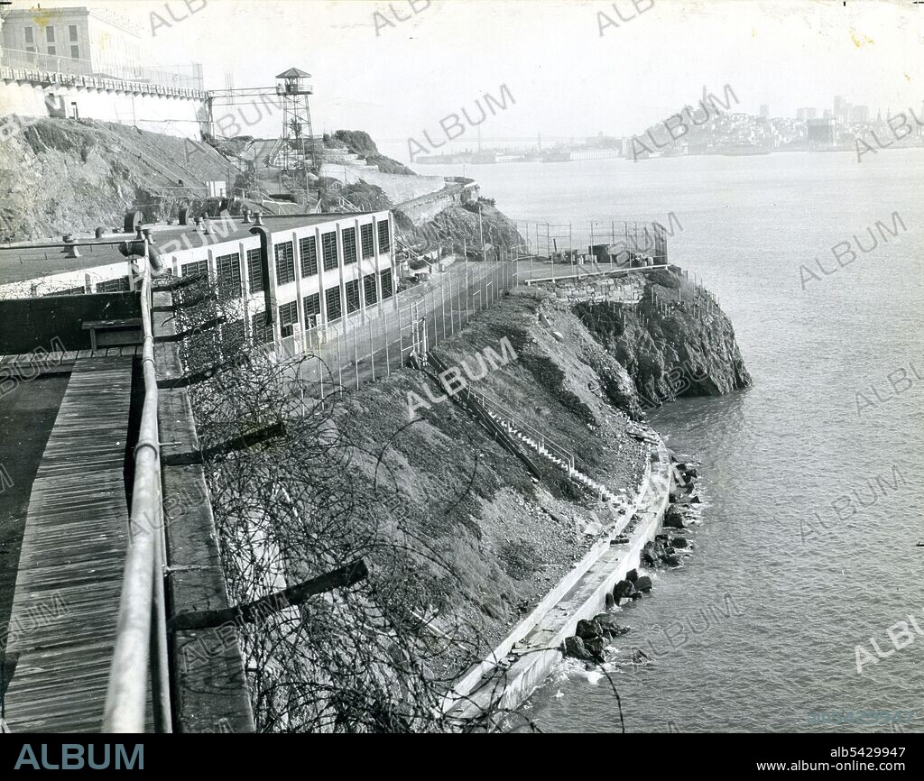 Alcatraz Prison, San Francisco, CA, circa 1940 - A view of the island taken from the industrial area with a guard tower, main cellhouse and San Francisco skyline in the background.