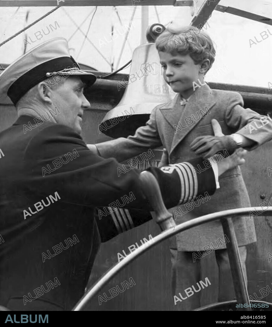 Stockholm 1952-06-07. Kronprins Carl Gustaf. På lördagseftermiddagen for de fyra yngsta Hagabarnen med S/S "Aeolus från Norr Mälarstrand till Borgholm. Båtfärden blev regning, men lillprinsen höll sig som förra sommaren helst på kommandobryggan. På bilden hjälper skepparn, kapten Carl Hjalmar Ericsson, ner honom från utkiken vid rodret. Foto: DN / TT / Kod: . ** SvD OUT **.