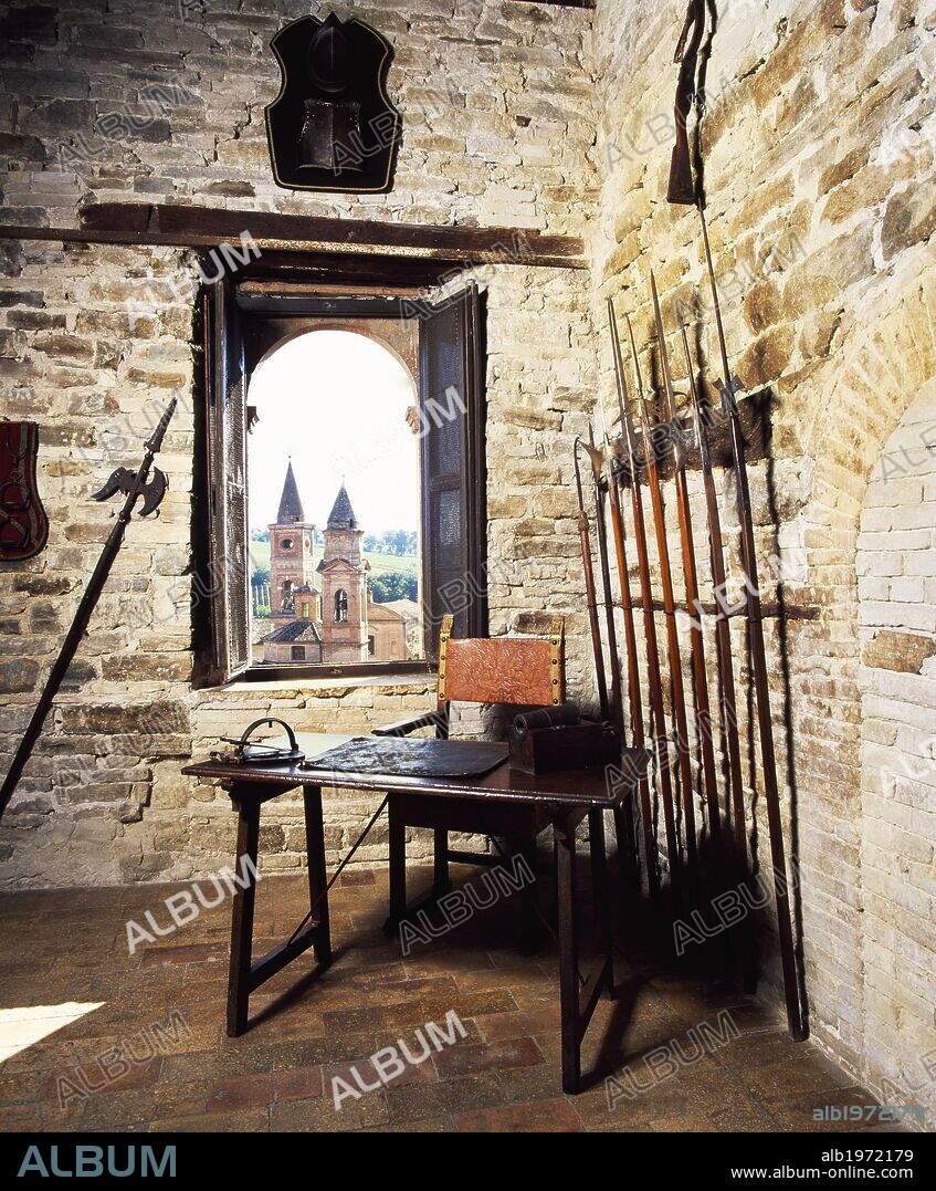 Glimpse of the armory, with medieval weapons and the steeples of Caldarola visible through the window, Pallotta Castle, Caldarola, Macerata, Marche. Italy.
