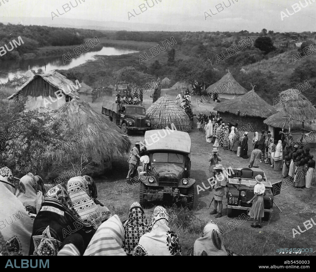 Village Arrival......In this scene from M-G-M's  "Mogambo", filmed in Africa, Clark Gable and members of his safari party have just arrived in a small native village. Gable, carrying gun, stenos in foreground, as Donald Sinden, member of his party, makes his photograph. Ava Gardner is about to step out of vehicle at left.
John Ford directed the Technicolor film with Sam Zimbalist producing. October 31, 1953.