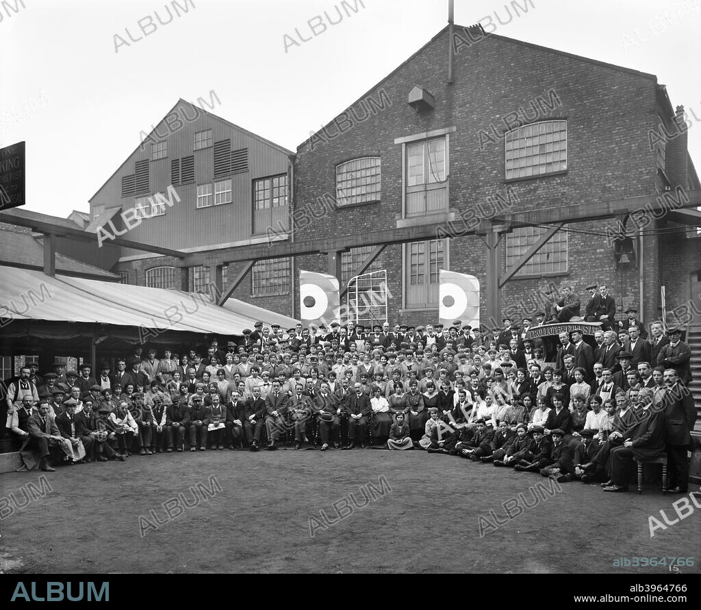 Aircraft manufacturing, Trollope and Colls Ltd, 17-25 Pleasant Street, Liverpool, December 1918. A group portrait showing staff posed outside the premises with two biplane wings positioned behind them. During the First World War builders Trollope & Colls Ltd. converted their timber yard to manufacture wings for biplanes.