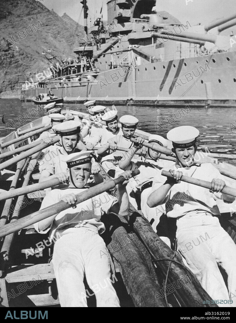 Mediterranean Sea: February 25, 1937. Seamen of the British Navy lay on the oars as they go through a drill in a cutter of the H.M.S. Royal Sovereign seen in the background.