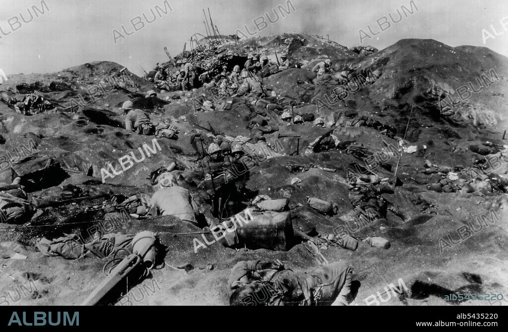 Marines Take 'Impregnable' Jap Pillbox On Iwo Jima -- American Marines, invading the Jap stronghold of Iwo Jima, Volcano Islands, dig in after taking what was an "Impregnable" enemy pillbox (center background). Note Marine in center digging foxhole and bodies, some in open, some partly covered by sand, which caption did not identify. These are fourth division marines in action February 19. February 22, 1945. (Photo by Joe Rosenthal, AP Wirephoto).