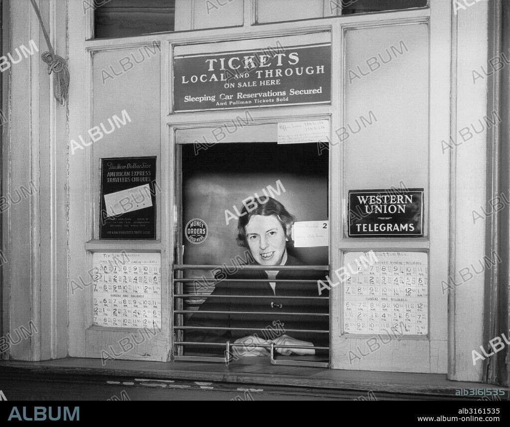 Oakland, California: c. 1946 A woman at at a railroad ticket counter selling tickets to San Francisco and Dutton Avenue in San Leandro, along with American Express Traveler's Cheques and Western Union telegrams.