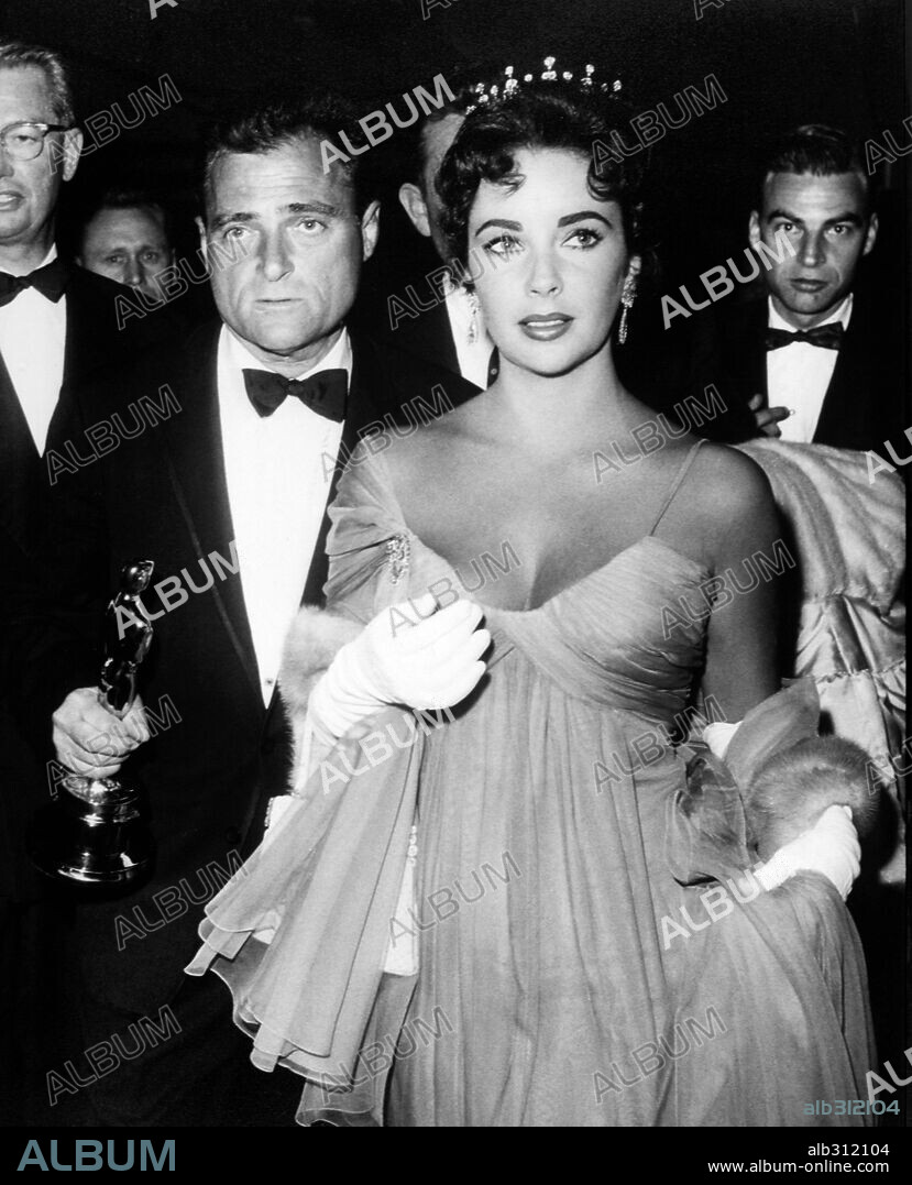 ELIZABETH TAYLOR y MIKE TODD. 29ª Edición de los Premios Oscar (1957). El productor Mike Todd con el premio a la mejor película "La vuelta al mundo en 80 días". Le acompaña su esposa y actriz Elisabeth Taylor. 1957