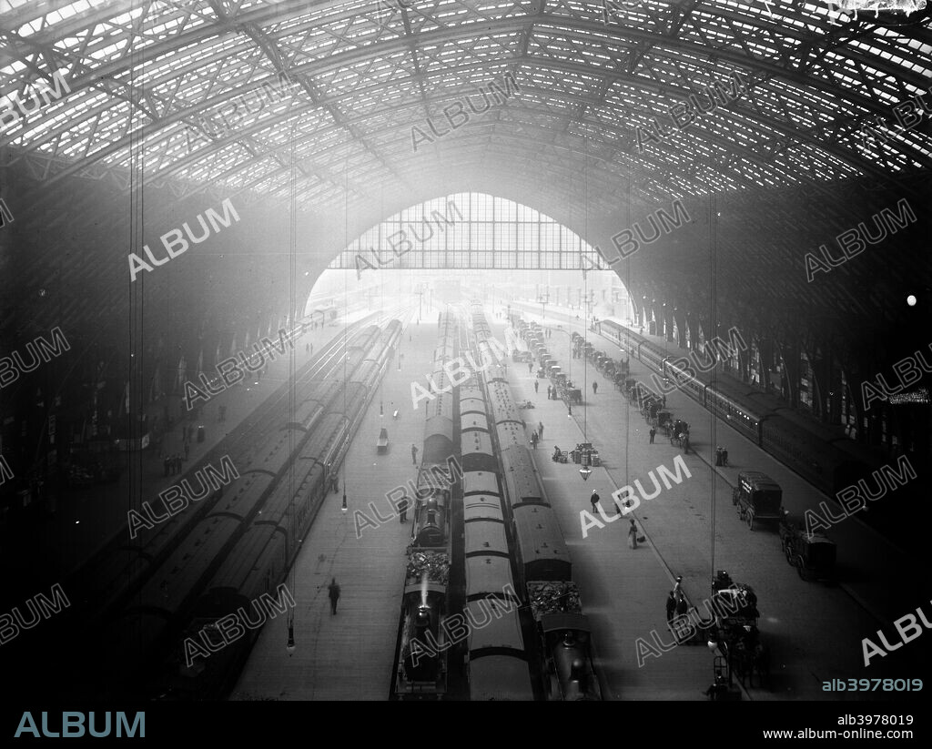 Interior view of St Pancras Station, Camden, London, c1895. The station was designed in 1868 by Sir George Gilbert Scott, and the civil engineer was William Henry Barlow. The wrought iron ribs spring from the platforms to cover a span of 240 feet and a length of 690 feet. Steam trains and horse drawn carriages are awaiting passengers.