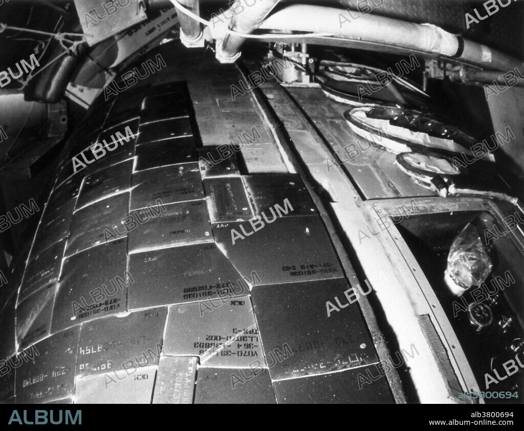 Thermal protective system of the Space Shuttle Columbia. STS-2, the second NASA Space Shuttle Mission, and the second flight of the Columbia, was originally set for launch on October 9, 1981, but leakage of nitrogen tetroxide oxidizer required removal, decontamination, and reapplication of more than 300 of Columbia's thermal protection system tiles. The leakage occurred in the forward oxidizer purge access panel at upper left. The chemical ran down the surface of the spacecraft, loosening the bond between the Orbiter's skin and the tiles. Below the access panel, circular ports for the orbital manoeuvring system nozzles are visible in this view of the starboard section of Columbia's nose, looking down and aft from a work platform at Launch Pad 39A. Kennedy Space Center, Florida, August 10, 1981.