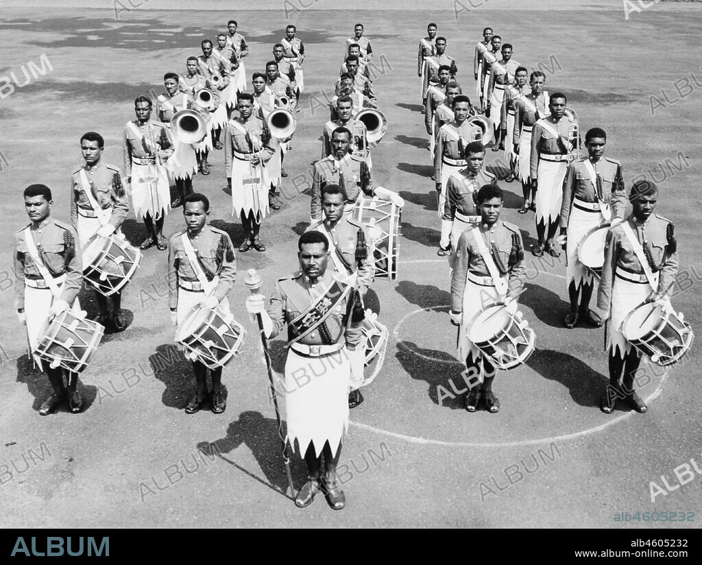 Fiji, Royal Fijian Military BandFronted by a Drum Major holding a staff, the 32-piece Royal Fijian Military Band stands in formation, ready to march. The band's instruments include drums, trombones, tubas and trumpets. Caption reads: This famous band of the Fijian military forces has toured in many countries throughout the world, 1965. 2005/010/1/14/9.