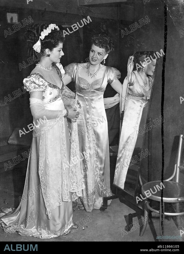 The British Film Festival organised by the "Daily mail" to mark the jubilee of the British Cinema and the foundation of the "Silver Star" National film award, was held at the Leicester Square theatre, London. Famous British film Stars reacted parts, in costume, they made memorable in British films over the years. Picture Shows: Phyllis Calvert (Clarissa) and Margaret Lockwood (Hester) wearing head-dress, putting finishing touches to their costumes before re-enacting their roles in "man in grey". 3 March 1946.