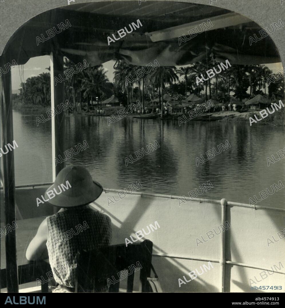 'On a Steamer on the Lualaba River, Belgian Congo - A Native Village at the Water's Edge', c1930s. The Lualaba River flows entirely within the eastern Democratic Republic of the Congo.  Leopold II of Belgium acquired rights to the Congo at the Berlin Conference in 1885, the Belgian Congo gained independence in 1960. From "Tour of the World". [Keystone View Company, Meadville, Pa., New York, Chicago, London].