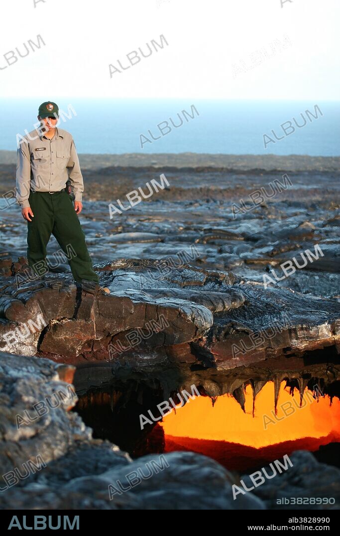 Park ranger near a skylight in a lava tube, a natural conduit through which lava travels beneath the surface of a lava flow, in Kilauea Volcano, Hawaii. Skylights usually form when part of a tube's roof collapses.