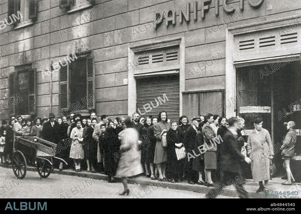 GM ITALIA a small crowd in resigned waiting, the queue for bread in front of an exercise that distributes the rations to families on presentation of the ration cards, Rome 1941.
