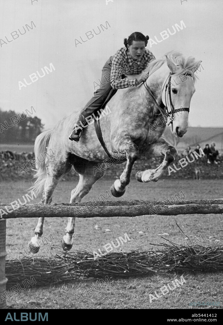 Famous Pair In Training -- A fine action shot of Miss Pat Smythe and her equally-famous grey horse "Tosca", as they practise in the paddock of her home at Miserden (Glos) in preparation for the Olympic Horse Trials at Badminton. 24-year-old Pat Smythe, the famous show-jumper, who was recently elected "Sportswoman of the Year", is now in strict training for the Olympic Horse Trials taking place at Badminton on April 21st, 22nd, and 23rd. She will be competing for the first time since returning from her triumphant tour of American and Canada last autumn. April 20, 1954. (Photo by Fox Photos).