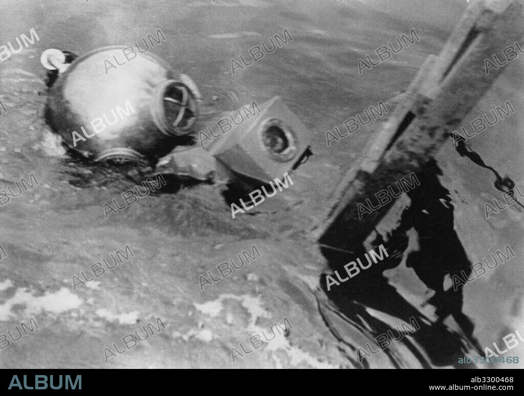 Berlin, Germany:  c. 1932.Photographer and photojopurnalist Willie Ruge prepares to take the first underwater photographs outside of a diving bell. Ruge commented, " Going down with our camera was an unbelievable task. Regardless of our 36 pound shoes and our 284 pound costumes, we couldn't for the life of us maintain a perpendicular position".