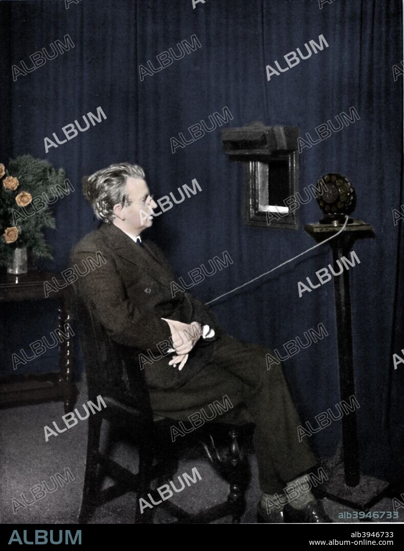 John Logie Baird (1888-1946), Scottish electrical engineer and pioneer of television, 1920s. Baird giving an early television ('Seeing by wireless') demonstration. The image is of someone holding two dolls. Baird began experimenting with imaging systems in the early 1920s. In 1924 he transmitted outline images over wires and by 1925 he was able to transmit recognisable human faces. In 1926 he started the world's first television station, which he named 2TV. (Colorised black and white print).