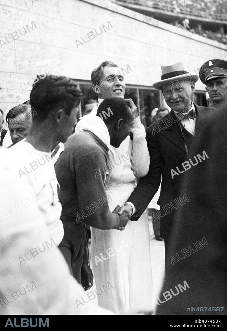 GERMANY BERLIN 1936-08. Orig. caption ... OLYMPIC MATCHES. The President of the Organizing Committee for the XI. Olympiad Dr. Lewald greets Jesse Owens for his 2nd gold medal, next to him the second, Lutz Long - Germany. Photo: Bilderdienst Bittner / AB Text & Bilder / SVT / Code: 5600 Folder: Olympiareportage Längdhopp I 264d OS 1936 i Berlin Sommar-OS Handslag persons: LUZ LONG; LUTZ LONG; JESSE OWENS; THEODOR LEWALD sites: USA *; BERLIN; TYSKLAND PhotoDate: 1936-08- ??.