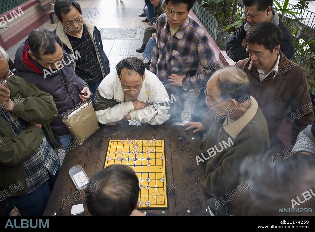 Two Chinese men playing Chinese Chess in the street, other men watching, Hong Kong, China, Asia.