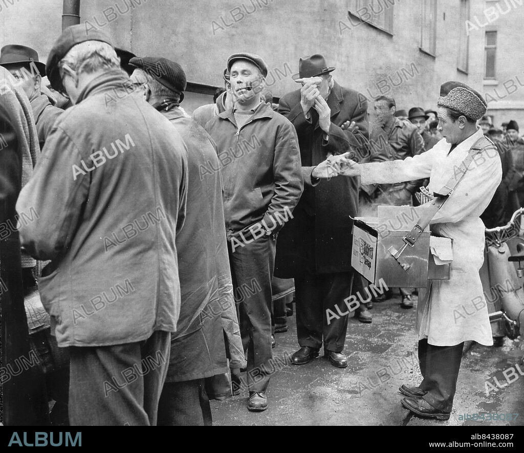 Stockholm 1963-04-03. Spritbrist på grund av strejken på Vin- & Spritcentralen, som är enda leverantör till Systembolaget. Stora spritlarmet gick på onsdagsmorgonen - systembutiken på Kocksgatan har fått påfyllning. Och genast växte kön runt kvarteret. Varma-korvgubben gjorde fina affärer bland de köande.. Foto: Arne Schweitz / Expressen / TT / Kod: 192. ** AFTONBLADET OUT **.