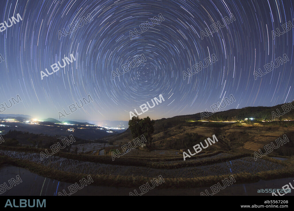Polar star trails circle around the north celestial pole above Honghe Hani Rice Terraces, a world heritage sites in southwest China. The Honghe Hani Rice terraces cascade down the towering slopes of the Ailao Mountains, carved out of dense forest over the past 1,300 years by Hani people. The irrigated terraces support paddy fields overlooking narrow valleys. In some places there are as many as 3,000 terraces between the lower edges of the forest and the valley floor.