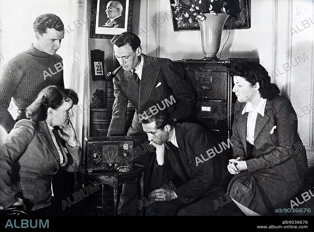 Photograph of Vichy French civilians listen to a radio broadcast by Admiral Jean Darlan (1881 1942) , French Admiral and political figure. He was Admiral of the Fleet and commander in chief of the French Navy in 1939 at the beginning of World War II. After France capitulated to Nazi Germany in 1940, Darlan served in the pro-German Vichy regime, becoming its deputy leader for a time.